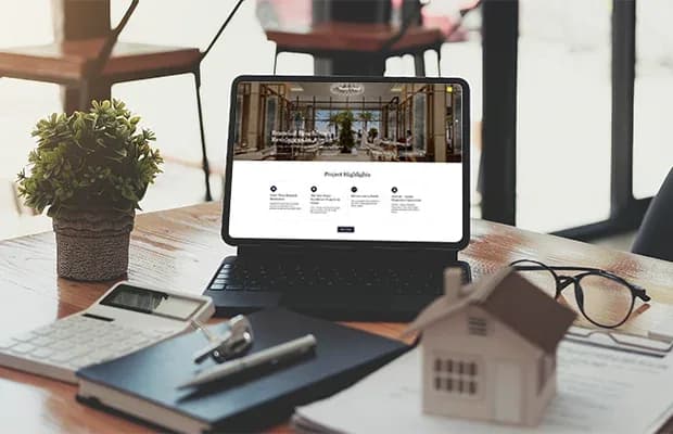 real estate website project interface on a desk with property documents and a house model, representing Prism Digital’s web design portfolio.