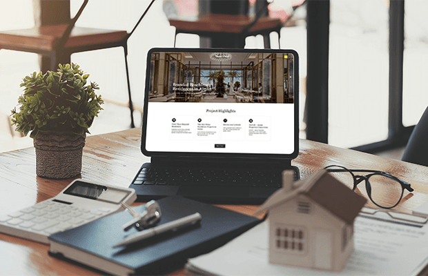 real estate website project interface on a desk with property documents and a house model, representing Prism Digital’s web design portfolio.